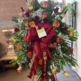 Standing spray of red and yellow roses with a large red ribbon