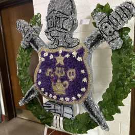 Floral standing tribute shaped like a knight in armor with a purple shield