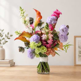 Colorful bouquet with calla lilies, hydrangeas, and snapdragons in a glass vase
