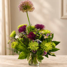 Purple and green mixed bouquet in a clear glass vase