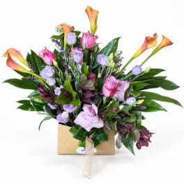 Mixed bouquet with pink roses, lavender blooms, and orange calla lilies in a box