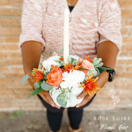 White pumpkin centerpiece with orange and white flowers and a candle