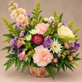Mixed bouquet in a wooden basket with pink, white, and purple flowers