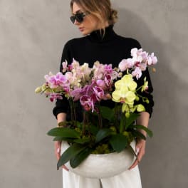Woman holding a large bowl of pink and yellow orchids