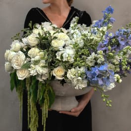 Large white and blue floral arrangement in a stone vase