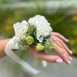 White and green wrist corsage on a hand with a white ribbon