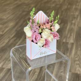 Pink and white roses arranged in a striped gift box