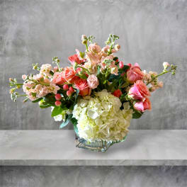 Pink roses and white hydrangeas arranged in a glass vase