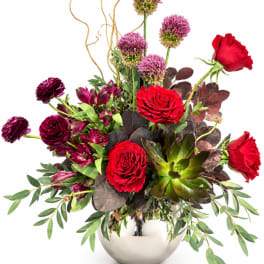 Red roses and purple blooms arranged in a silver vase