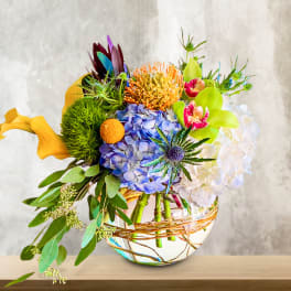 Colorful mixed bouquet in a round glass vase with a wicker wrap