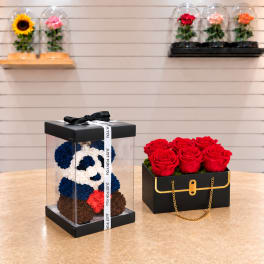 Two boxed rose arrangements, one in a clear gift box and one in a black box with red roses.