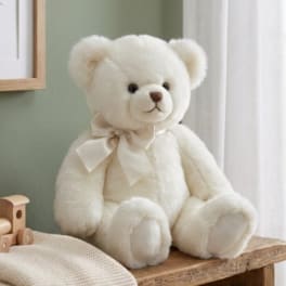 Cream teddy bear with a ribbon bow sitting on a wooden bench
