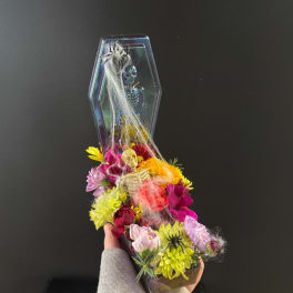Halloween floral arrangement in a coffin-shaped container with skulls and spider decorations