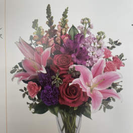 Pink lilies and roses arranged in a clear glass vase