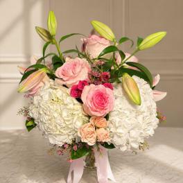Pink roses and white hydrangeas in a glass vase with lily buds