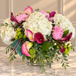 Pink and white floral arrangement with calla lilies and hydrangeas in a glass vase