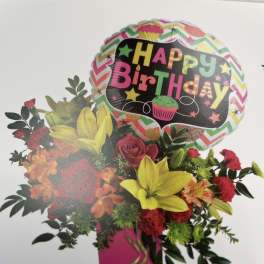 Birthday bouquet with roses, lilies, and a balloon in a pink vase