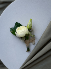 White boutonniere with a bud and dark green leaves