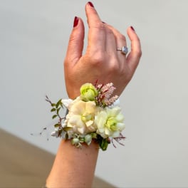 Small floral wrist corsage with pale cream and green blooms