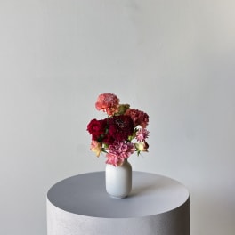 Small mixed flower arrangement in a white vase