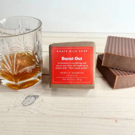 Soap bars beside a glass of amber liquid on a wooden surface