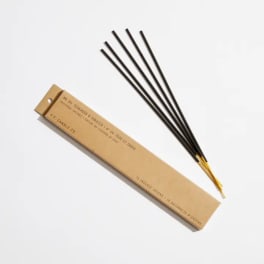 Box of incense sticks with several black sticks laid beside it
