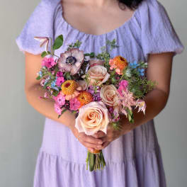 Woman holding a pastel bouquet of roses and mixed flowers