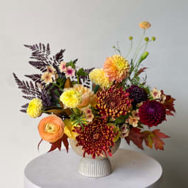 Mixed bouquet in a ribbed pedestal vase with chrysanthemums and ranunculus