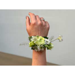 Hand wearing a floral wrist corsage with pale green and white blooms
