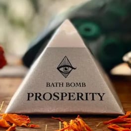 Triangular bath bomb box labeled "Prosperity" on a wooden surface