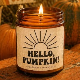 Lit amber candle in a glass jar labeled "Hello, Pumpkin!"