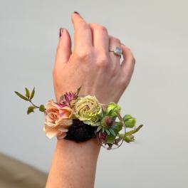 Floral wrist corsage with peach and pale yellow blooms