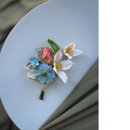 Small boutonniere with blue and white flowers and a pink rose