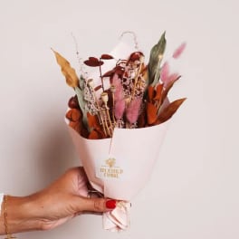 Handheld bouquet of dried flowers in white paper wrap