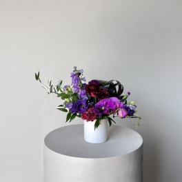 Purple and pink floral arrangement in a white vase