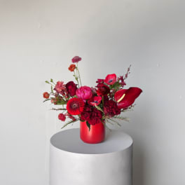 Red floral arrangement in a red vase on a pedestal
