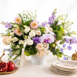 Mixed pastel flower arrangement in a white vase with purple and cream blooms