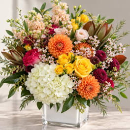 Mixed bouquet in a clear square vase with hydrangea, roses, and dahlias