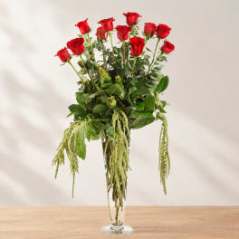 Tall vase arrangement of red roses with cascading greenery