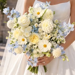 Bride holding a white and pale blue bouquet with roses and daisies