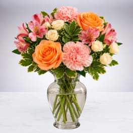 Mixed bouquet of roses, carnations, and alstroemeria in a glass vase