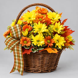 Yellow and orange daisies in a wicker basket with a plaid ribbon