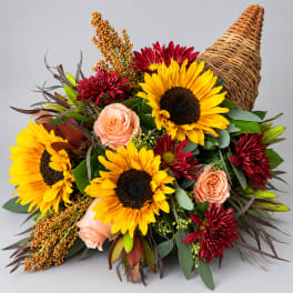 Bouquet of sunflowers, peach roses, and red chrysanthemums with a wicker cone wrap