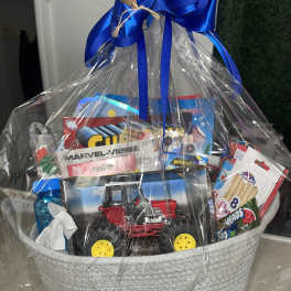 Gift basket with toys and candy wrapped in clear plastic and a blue ribbon