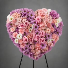 Heart-shaped floral arrangement with pink, purple, and white blooms