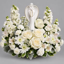 White floral arrangement with a praying angel figurine in the center