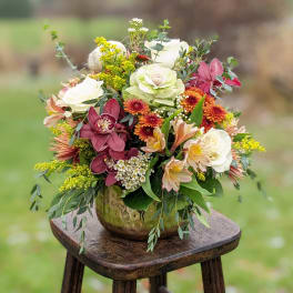 Mixed floral arrangement in a gold vase with white, pink, and orange blooms
