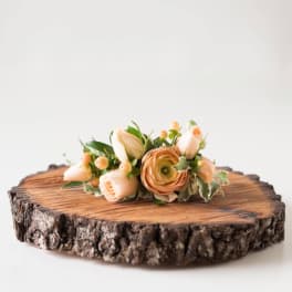 Peach floral arrangement on a wood slice base