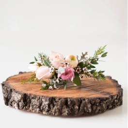 Small pastel floral arrangement on a wood slice