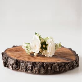 Small white floral corsage on a wood slice